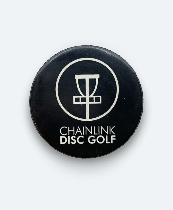 A hockey puck with ChainLink Disc Golf and TORONTO OPEN branding that can be used to get disc golf disc out of trees.