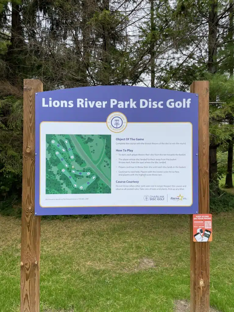 A disc golf course welcome sign with a course map and instructions to play at Lions River Park in Thamesford, Ontario.
